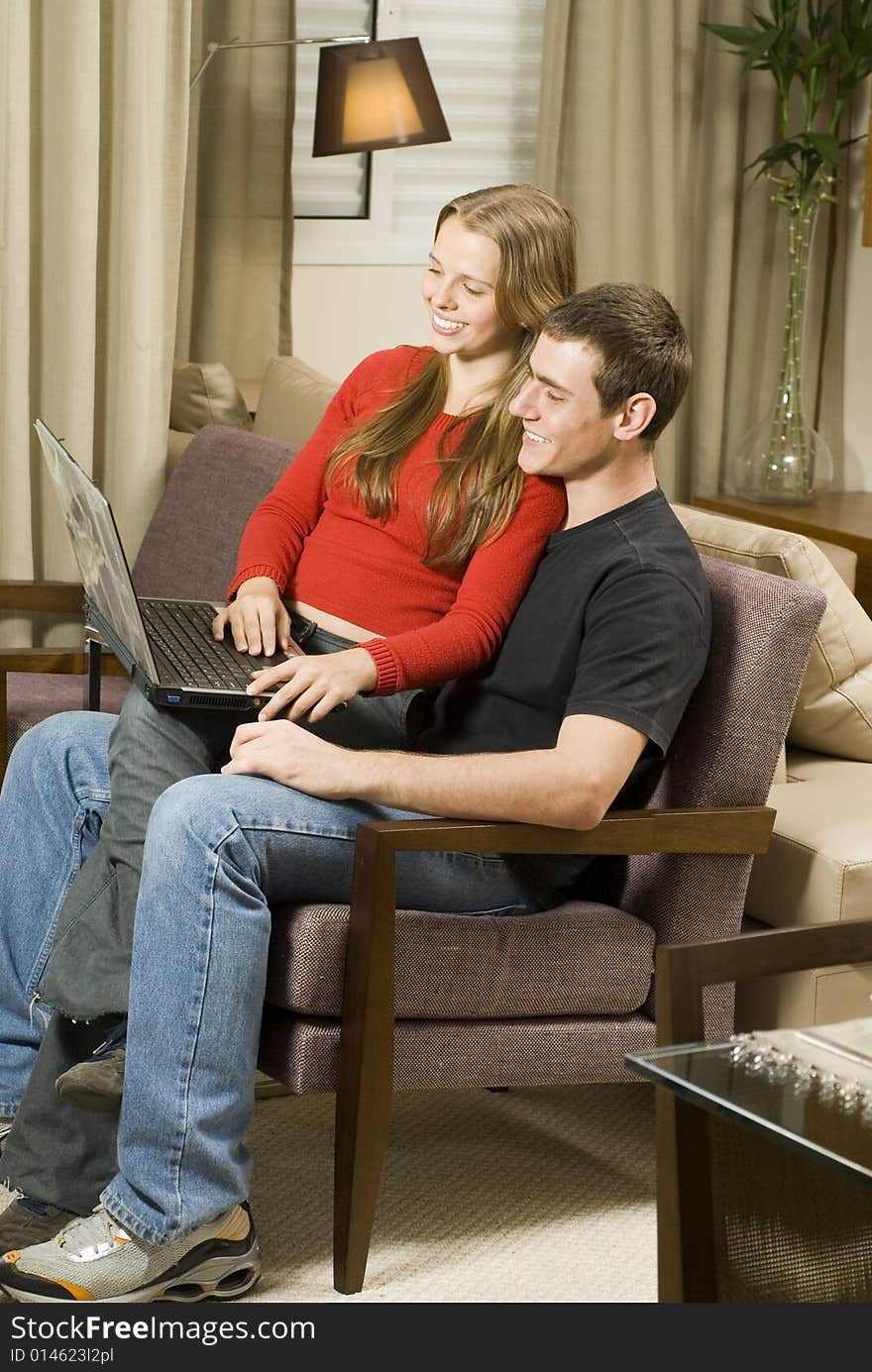 Young smiling, couple at home working on a laptop computer. Vertically framed photo. Young smiling, couple at home working on a laptop computer. Vertically framed photo.