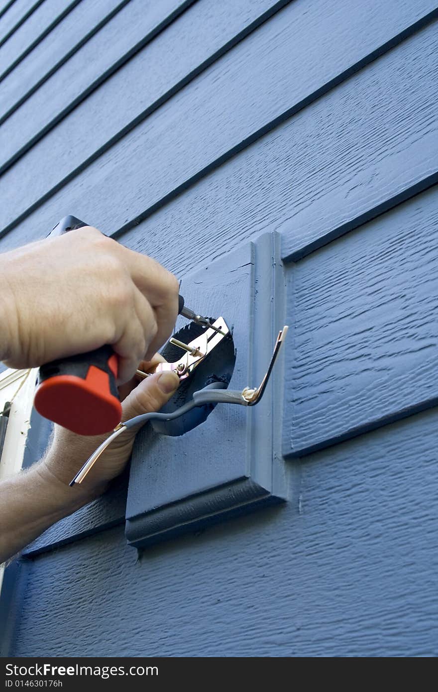 Hands fixing the wiring for a light fixture on a house. Vertically framed photo. Hands fixing the wiring for a light fixture on a house. Vertically framed photo.