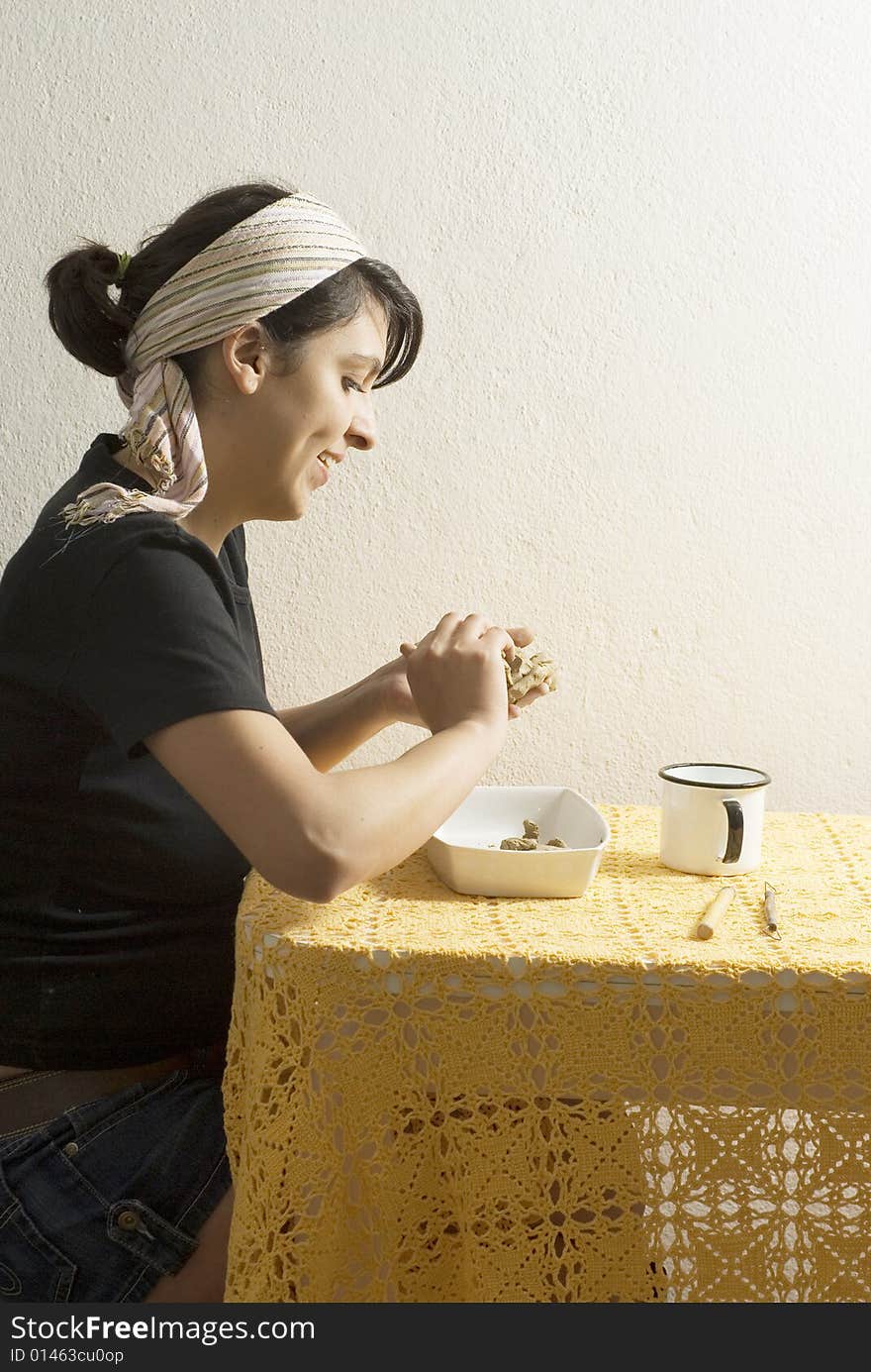 Artist seated at a table molding clay. Vertically framed photo. Artist seated at a table molding clay. Vertically framed photo.