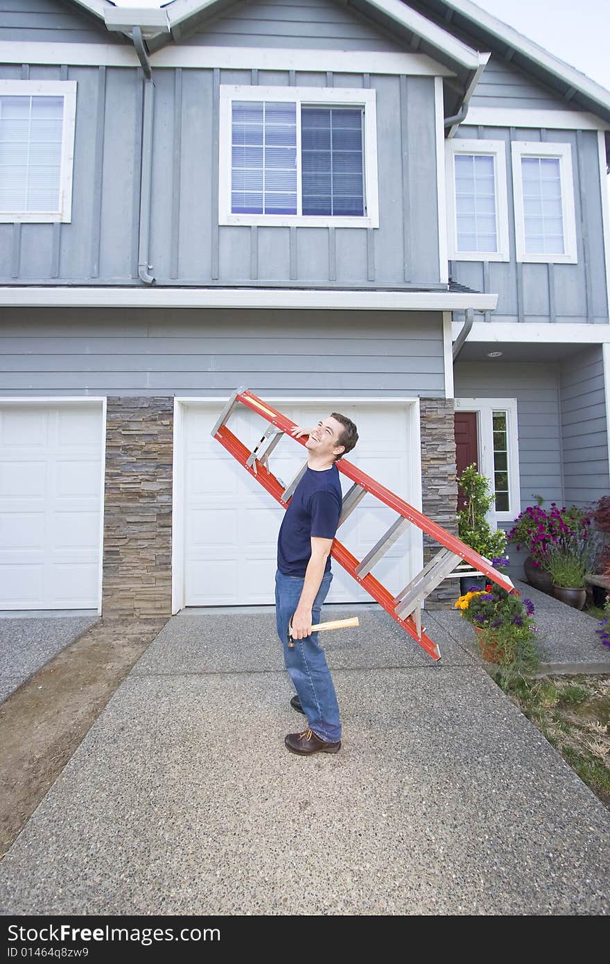 Laughing man standing in front of house holding ladder and hammer. Vertically framed photo. Laughing man standing in front of house holding ladder and hammer. Vertically framed photo.