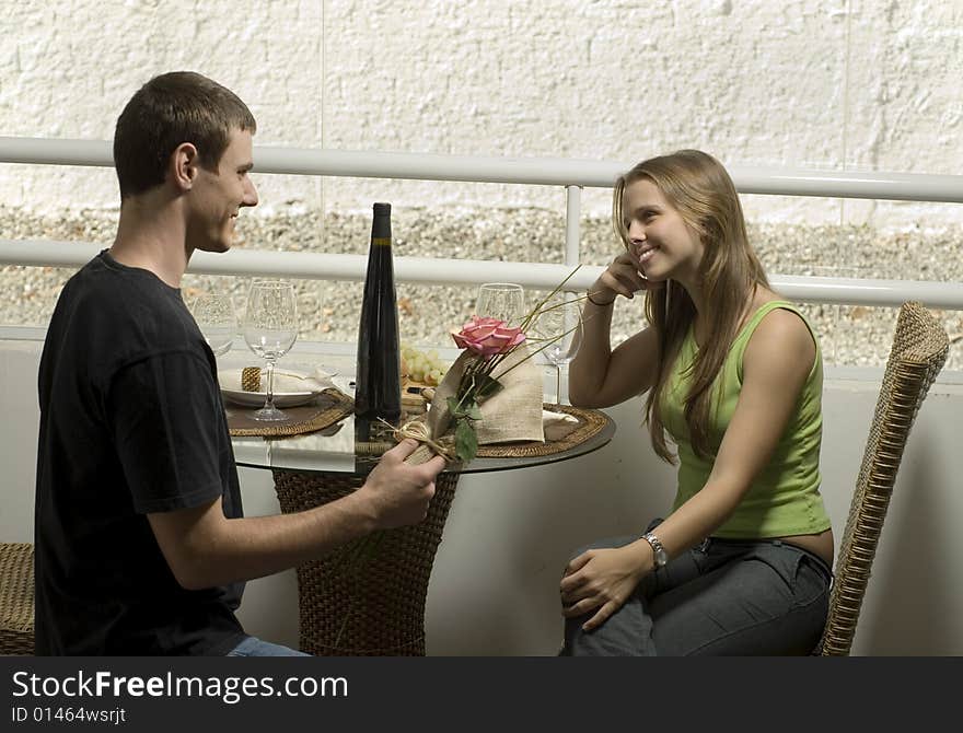 Couple sitting close looking at a flower and smiling. Horizontally framed photo. Couple sitting close looking at a flower and smiling. Horizontally framed photo.