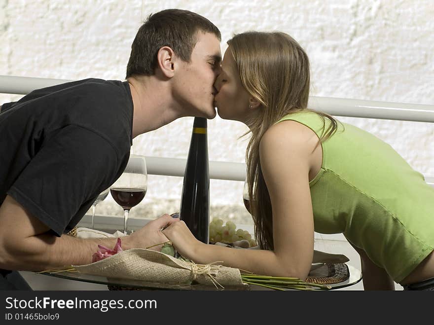 Couple leaning across a table kissing and holding hands. Horizontally framed photo. Couple leaning across a table kissing and holding hands. Horizontally framed photo.