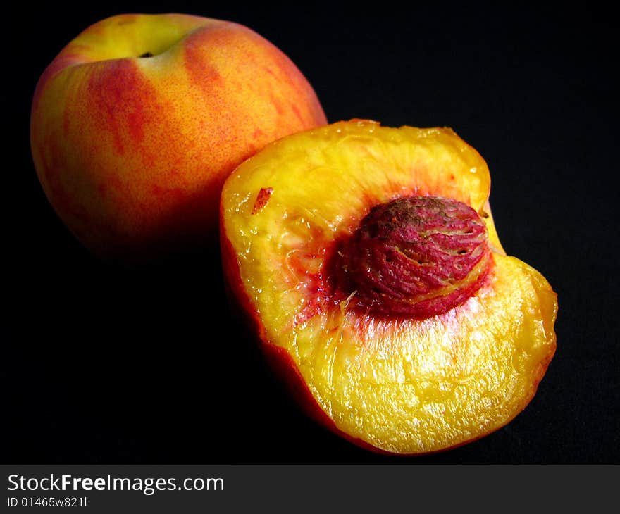Two ripe peaches on a black background