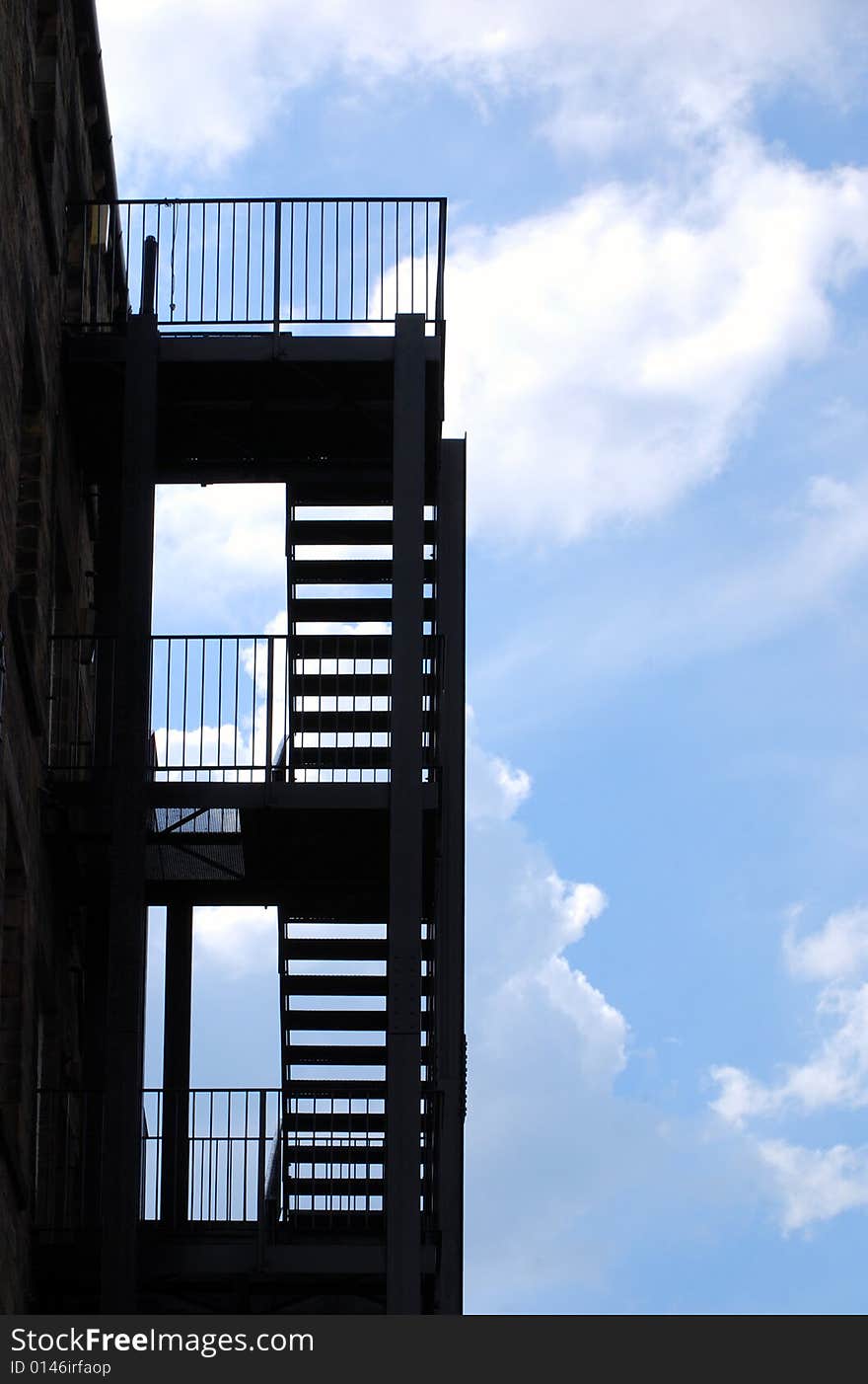 Silhouette of fire escape against cloudy blue sky