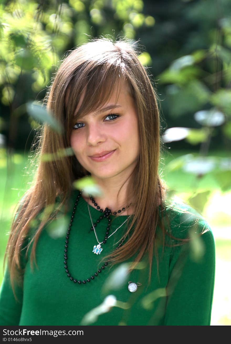 Photo presents a teenager behind the summer leaf. Photo presents a teenager behind the summer leaf