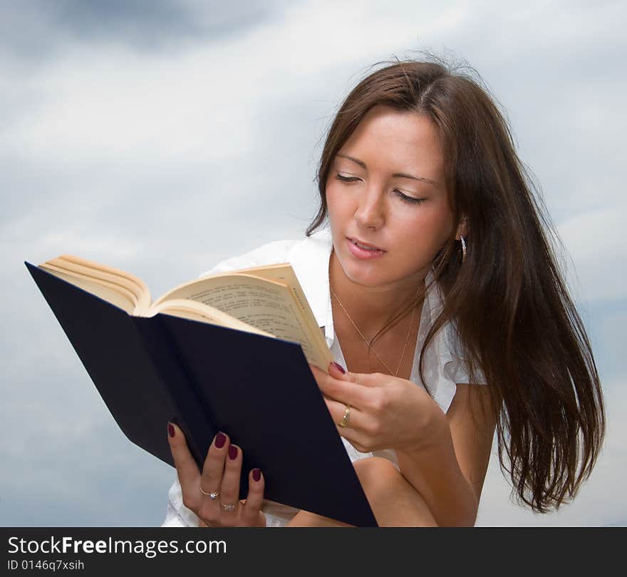 Young cute girl reads a book outdoors. Young cute girl reads a book outdoors