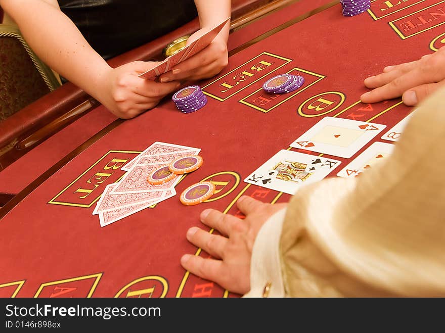 Cards in hands are on red table in casino. Cards in hands are on red table in casino