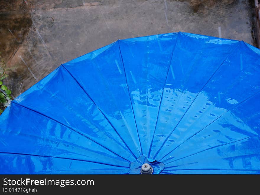 Blue umbrella on a terrace during a quick rain storm. Blue umbrella on a terrace during a quick rain storm