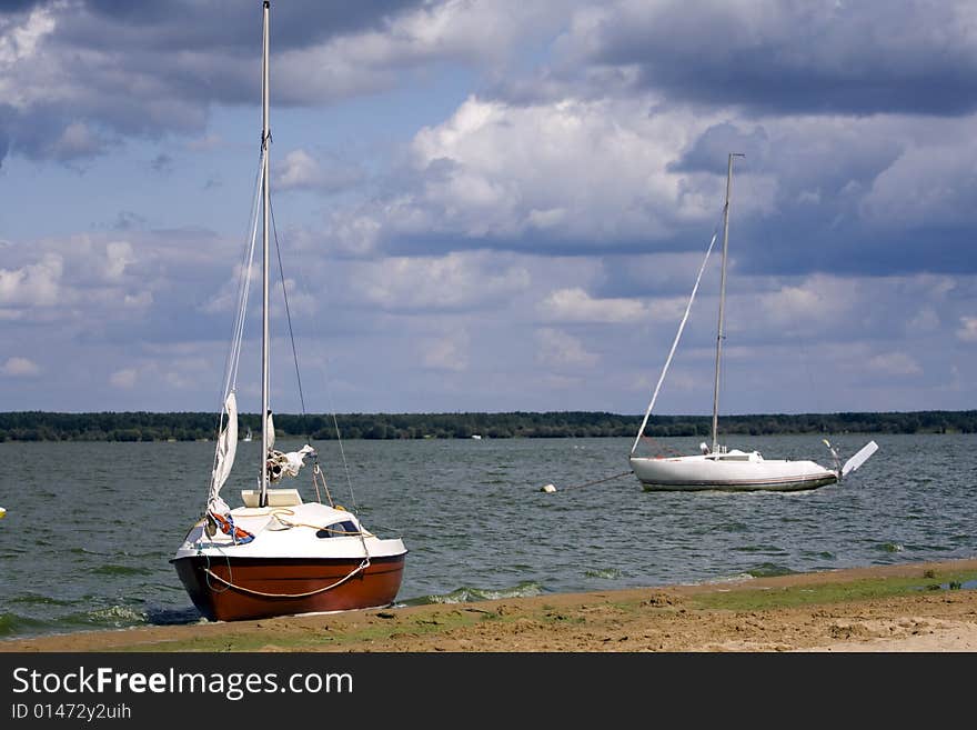 Two, small yachts at the sandy lakeside. Two, small yachts at the sandy lakeside