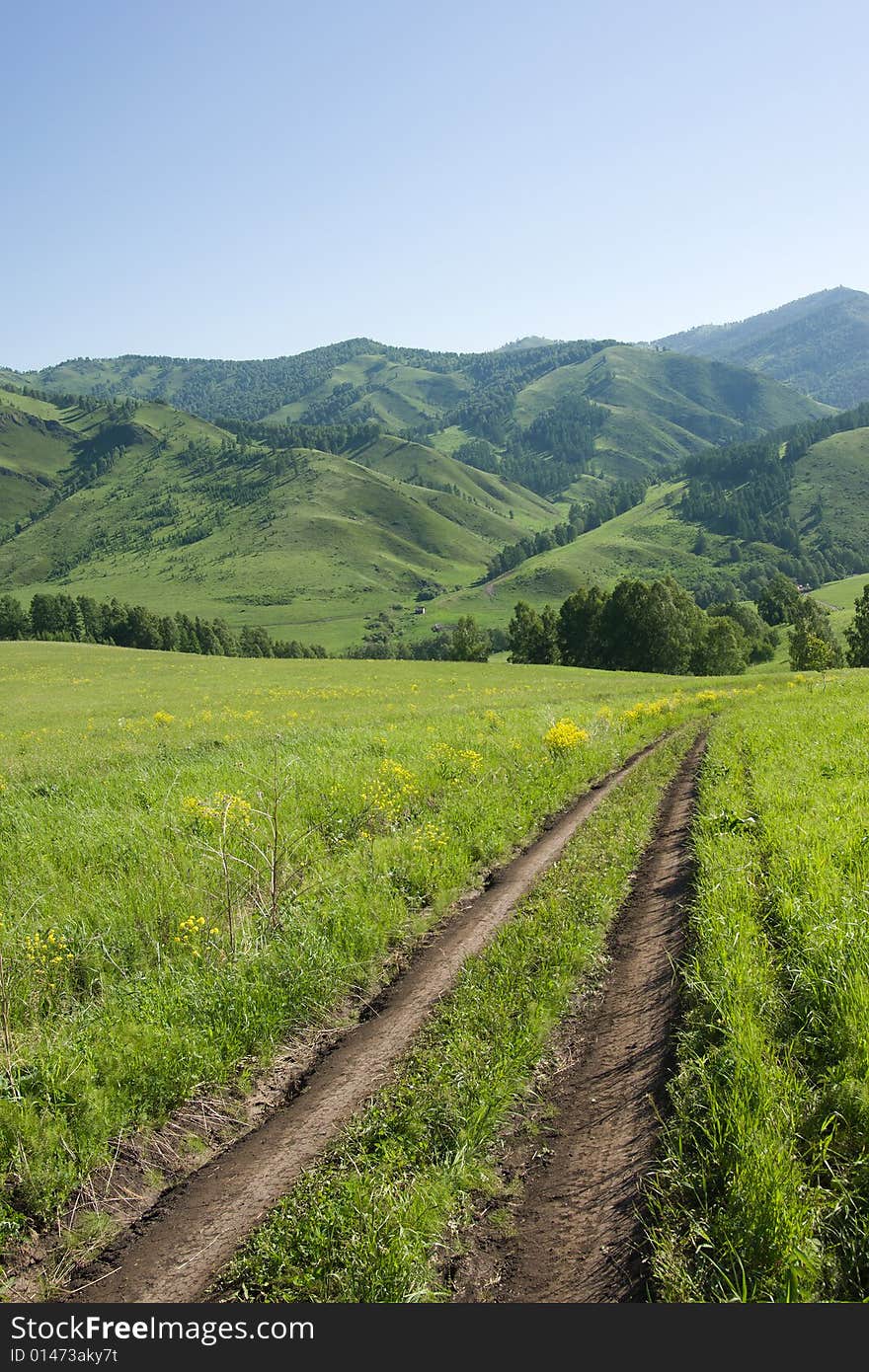 Road in mountains with green forest on blue sky. Road in mountains with green forest on blue sky