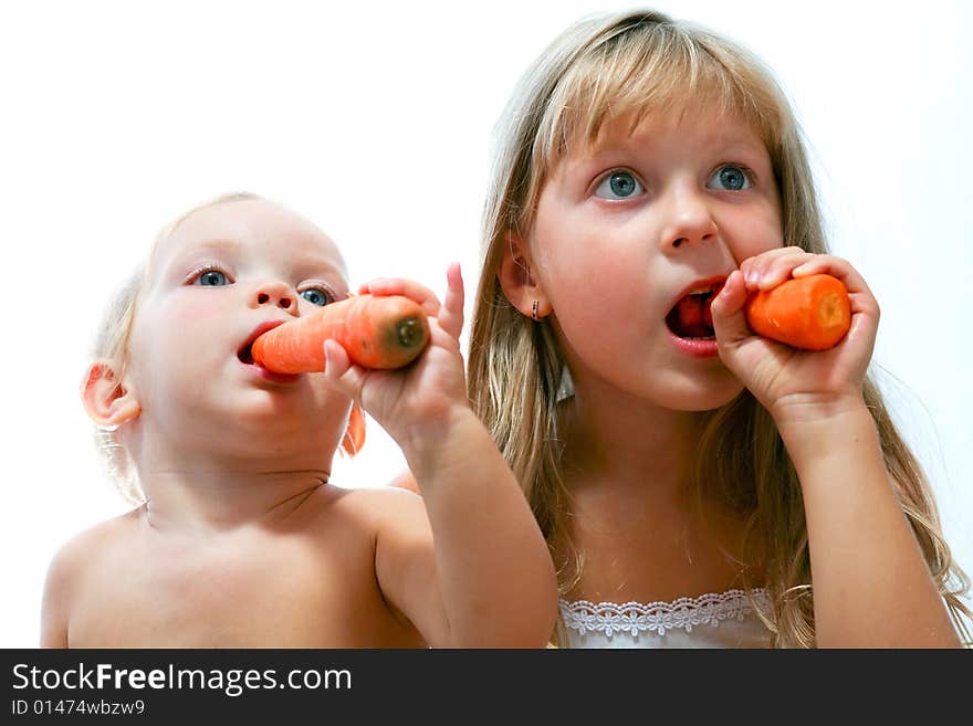 An image of two sisters eating orange carrot