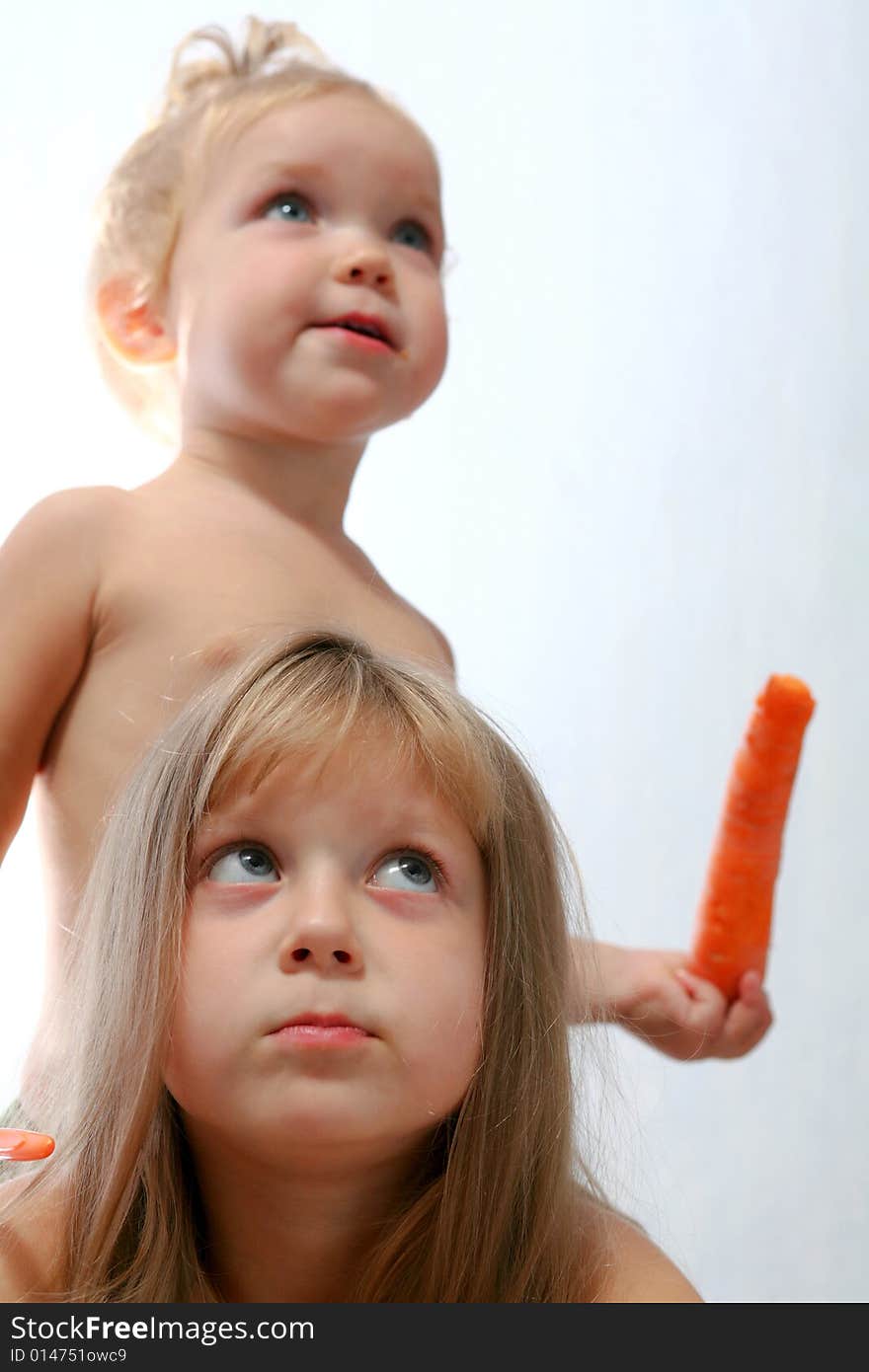 An image of two sisters eating orange carrot