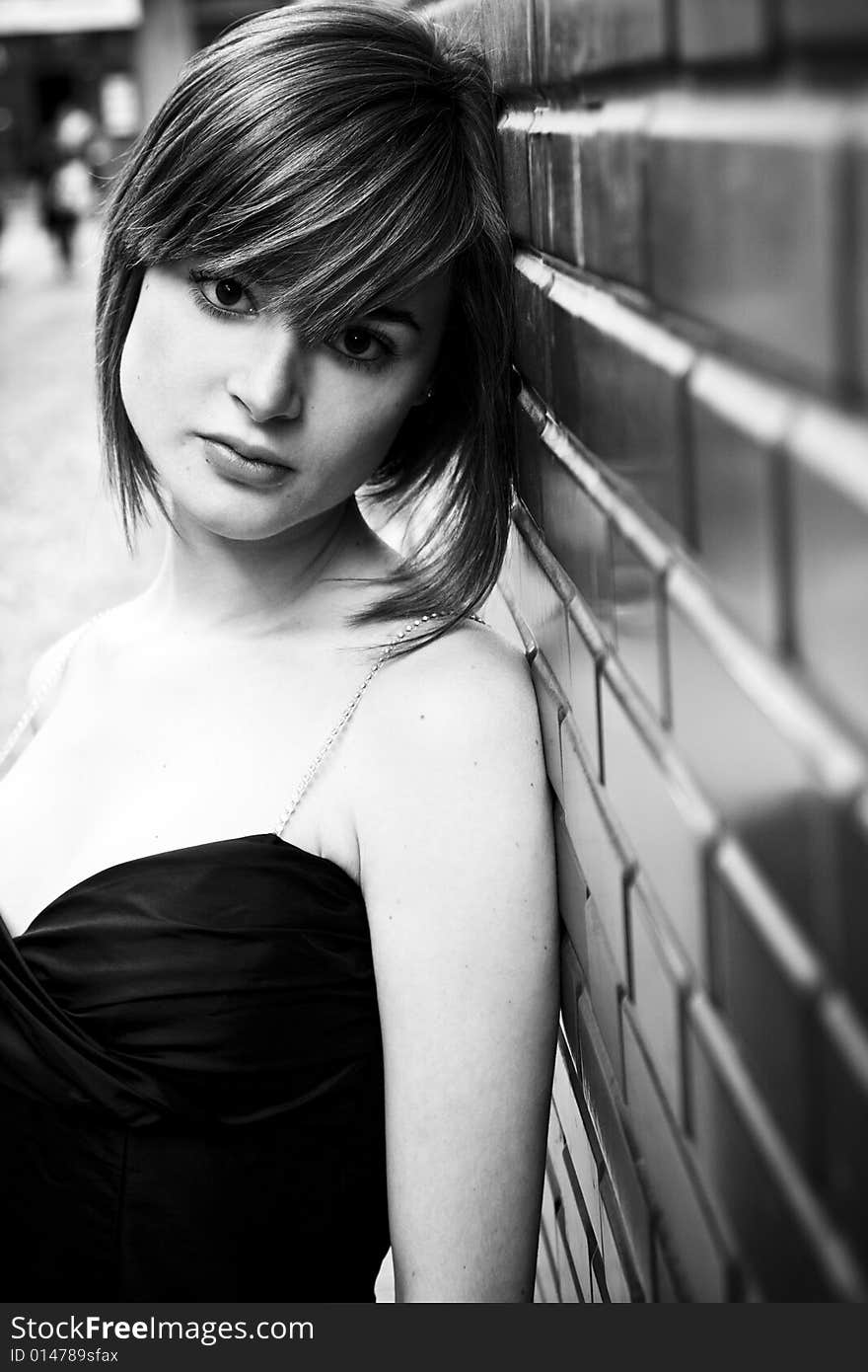 Young elegantly dressed woman on brick wall in black and white. Young elegantly dressed woman on brick wall in black and white.