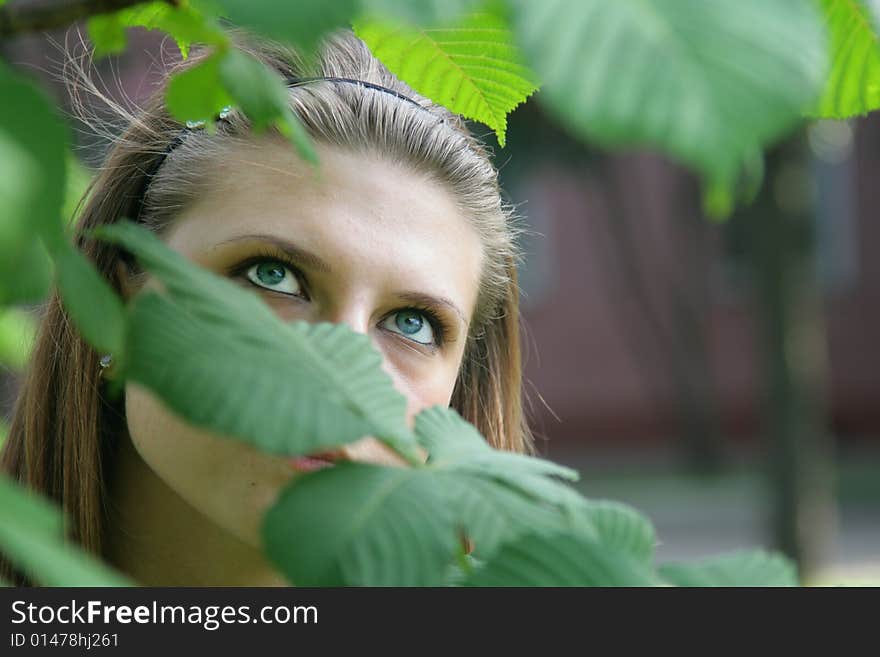 The blue-eyed girl admires green leaves