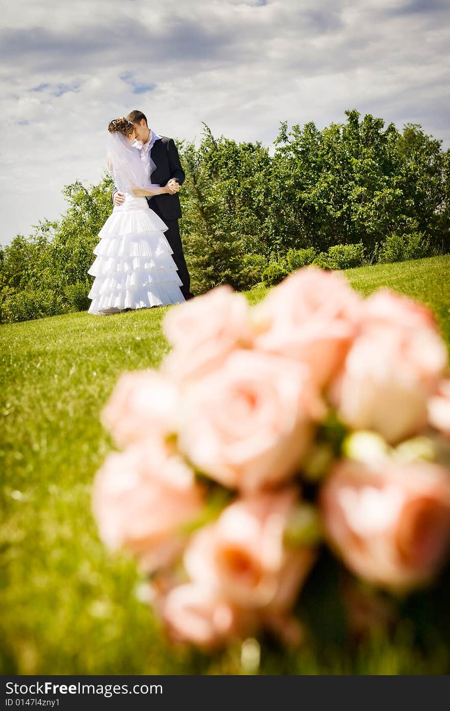 Groom kisses bride and a flower bouquet near by. Groom kisses bride and a flower bouquet near by