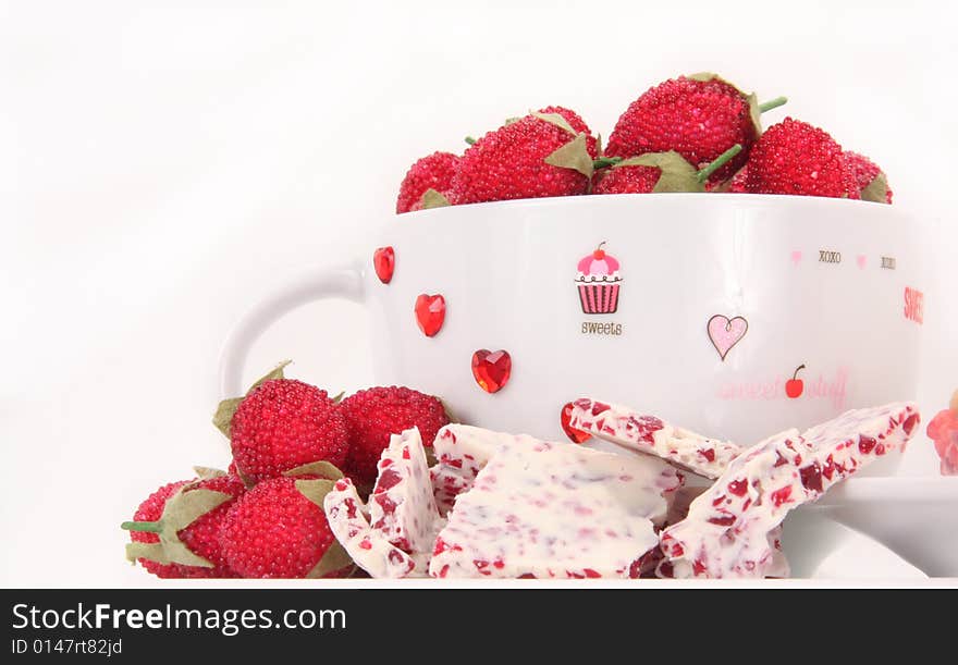 Raspberry and white chocolate candy with a decorated valentine cup on a white background. Raspberry and white chocolate candy with a decorated valentine cup on a white background