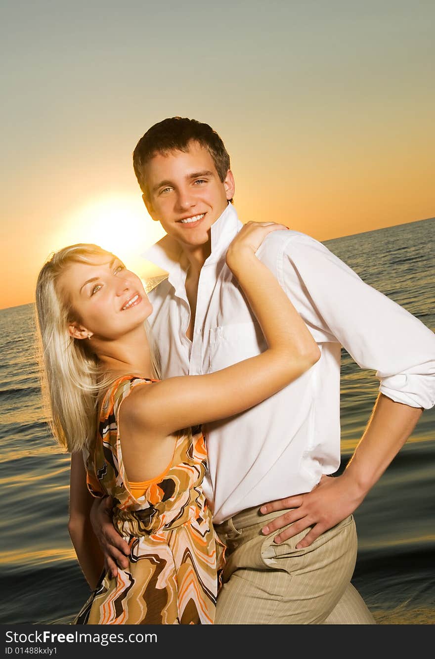 Young couple in love near the ocean at sunset