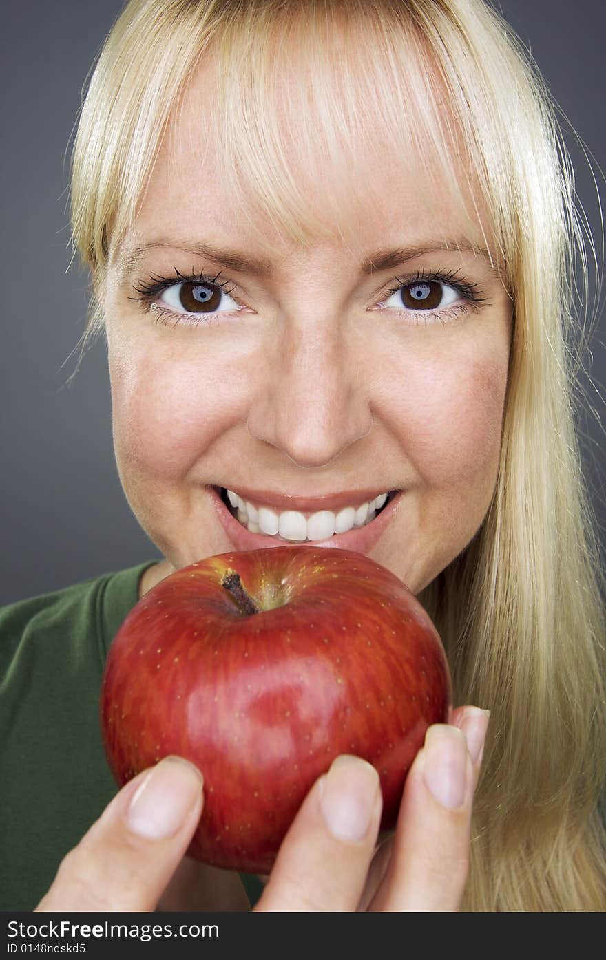 Beautiful Woman With Apple Against A Grey Background.