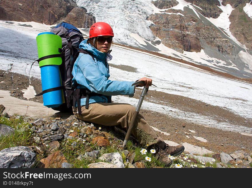 Backpacker girl with ice-axe in high Caucasus mountains