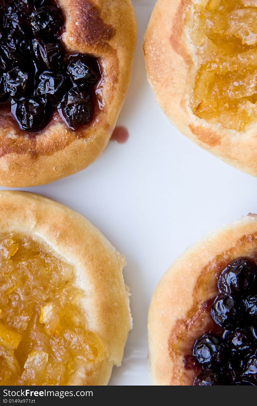 Four cakes. Two with a cherry, two with a lemon, are located on photo corners on white plate