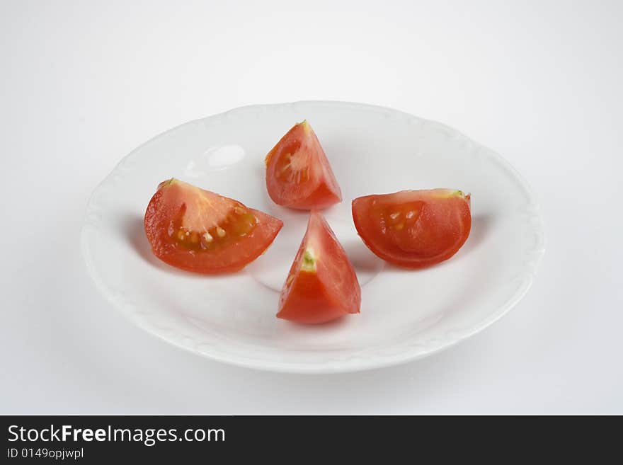 Tomato divided on quartos on white plate. Tomato divided on quartos on white plate