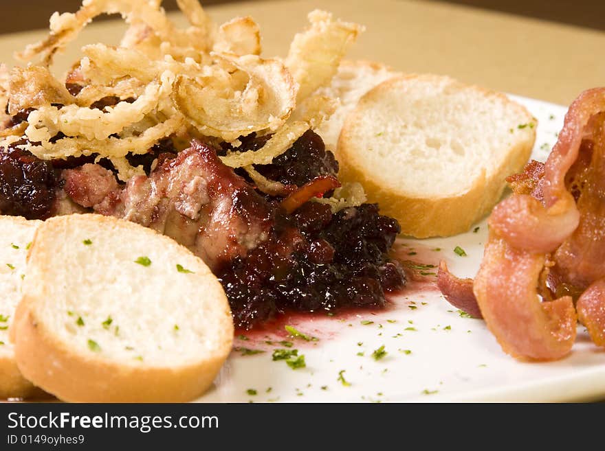 A platter of pate with cranberry sauce, bacon, and slices of bread. A platter of pate with cranberry sauce, bacon, and slices of bread