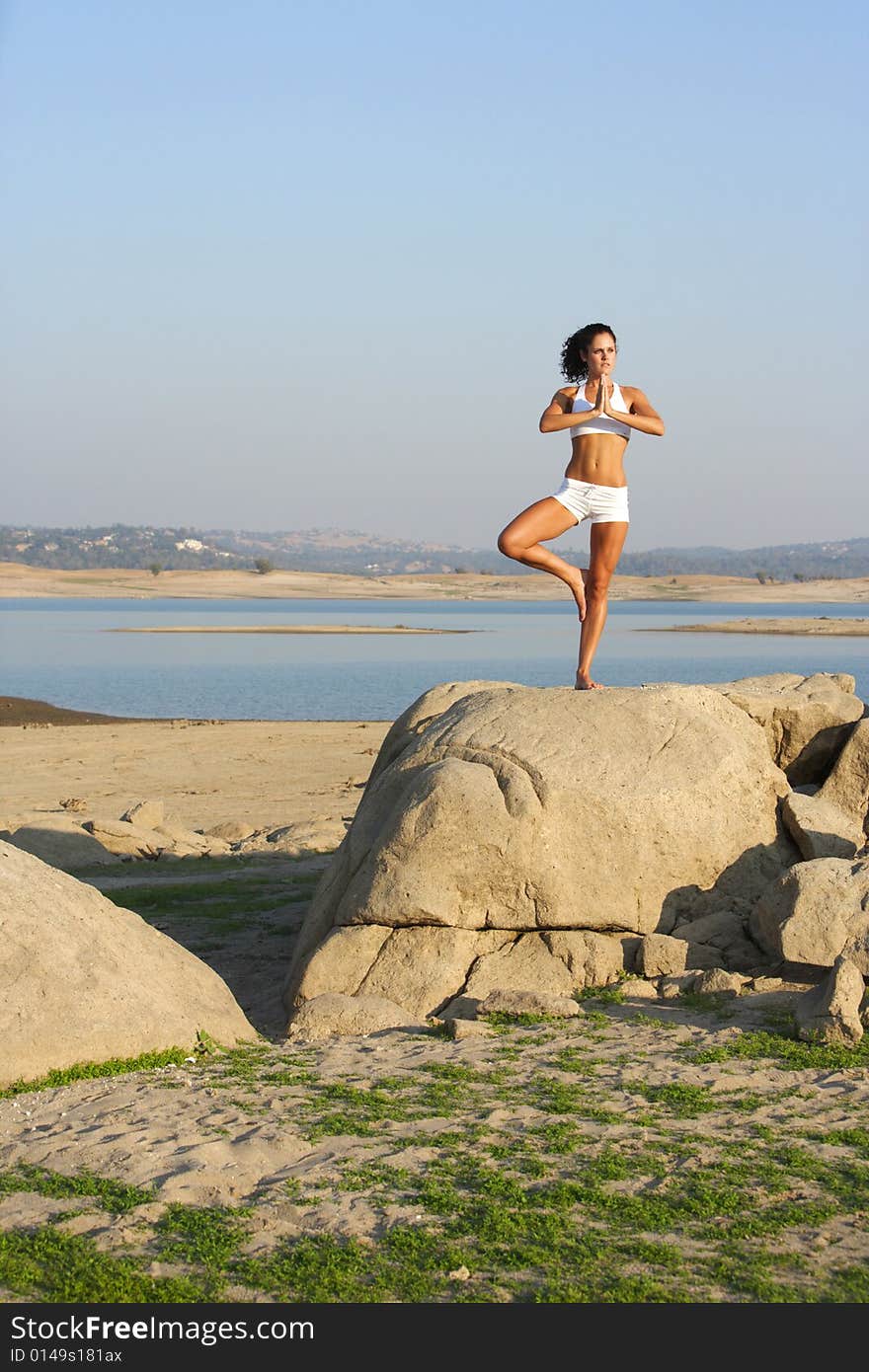 A young woman on top of a rock doing yoga