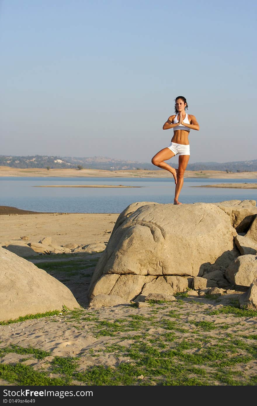 A young woman on top of a rock doing yoga