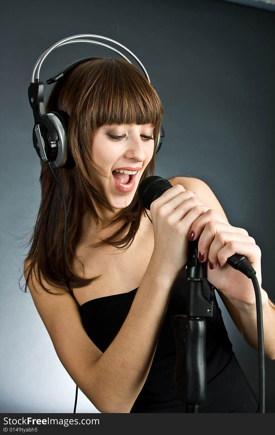 Woman in headphones Singing into Microphone