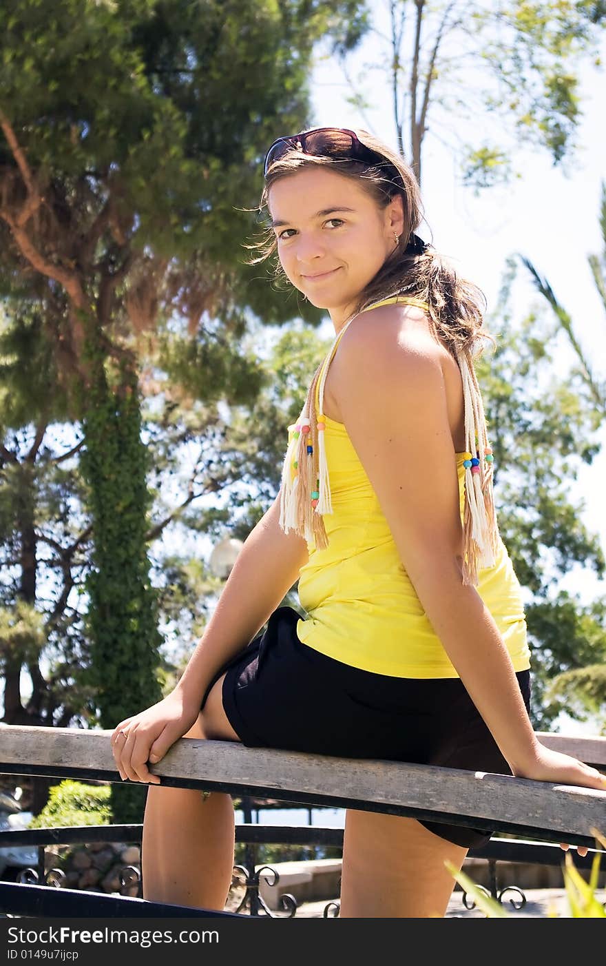 Smiling girl sitting on bridge fence