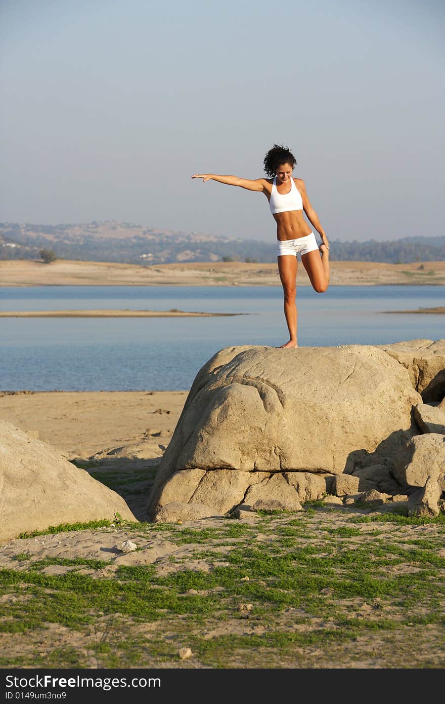 A young woman on top of a rock doing yoga