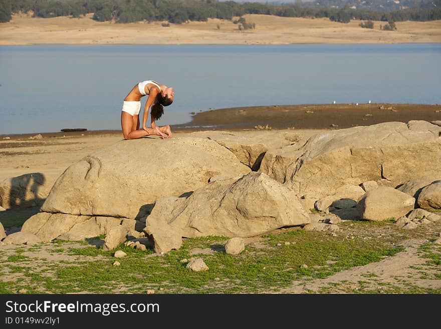 A Young Woman On Top Of A Rock Doing Yoga