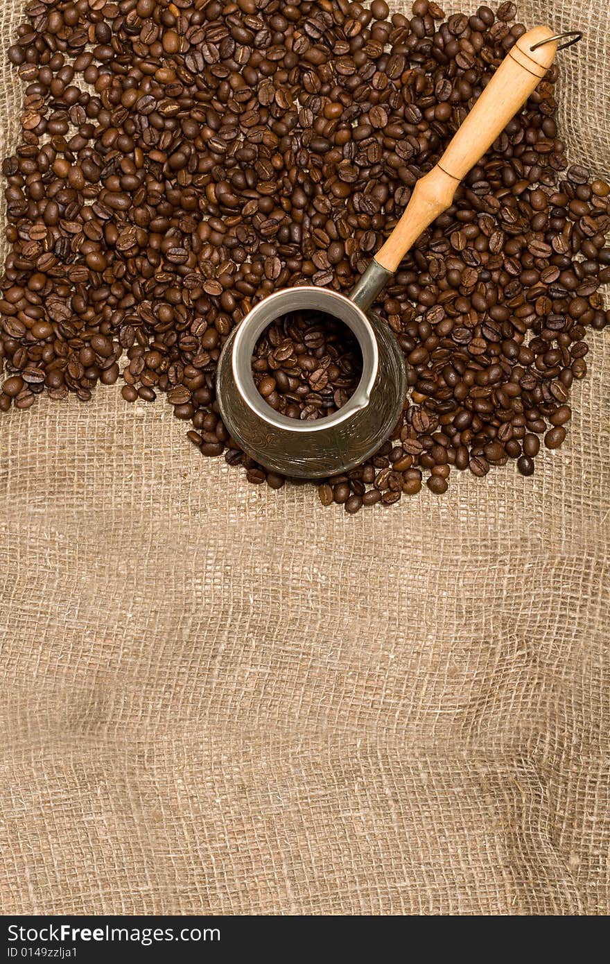 Cezve with freshly roasted coffee beans on sackcloth