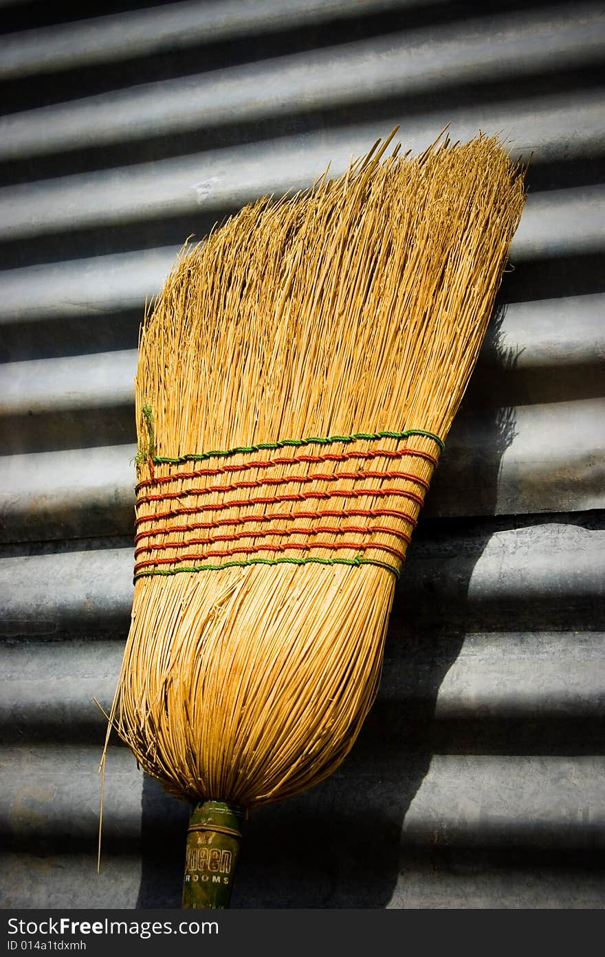 Broom head sitting up on corrigated iron wall