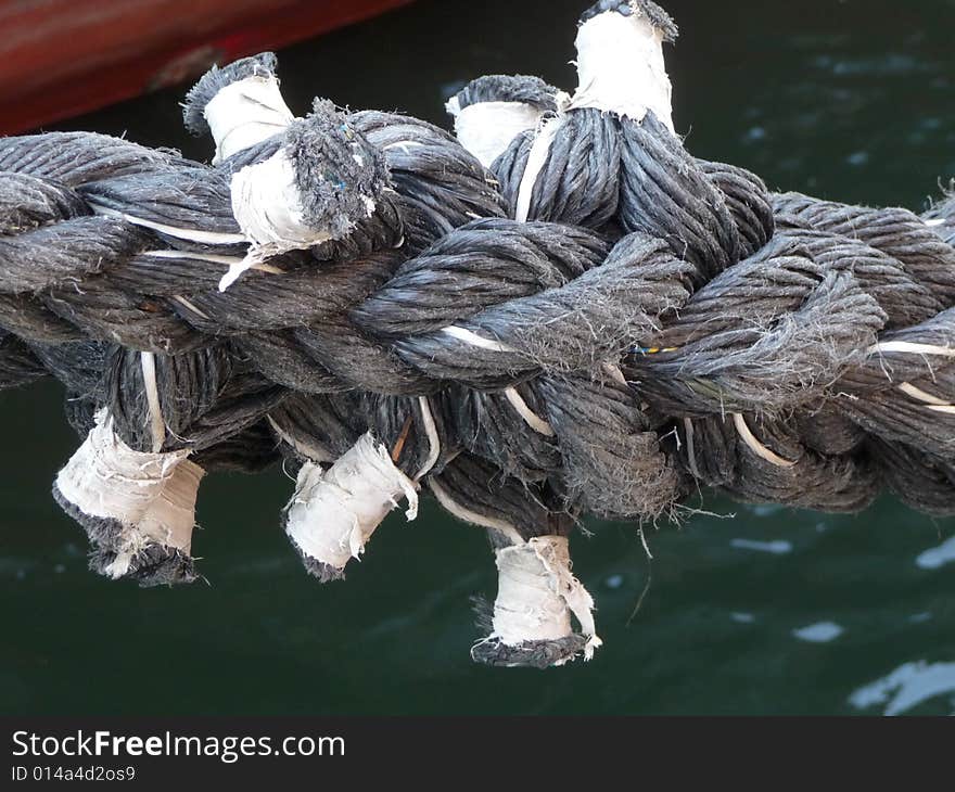 A very knotted rope between a yacht and the dock. A very knotted rope between a yacht and the dock