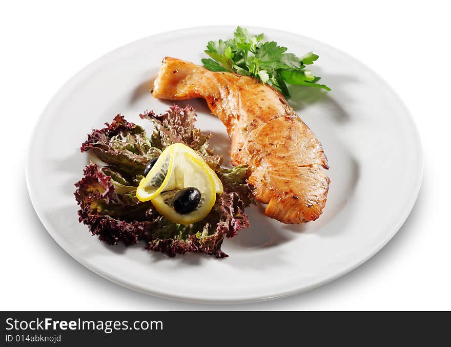 Steak from Filleted Fish (Salmon) with Lemon Slice Olive and Salad on a Plate. Isolated on White Background. Steak from Filleted Fish (Salmon) with Lemon Slice Olive and Salad on a Plate. Isolated on White Background