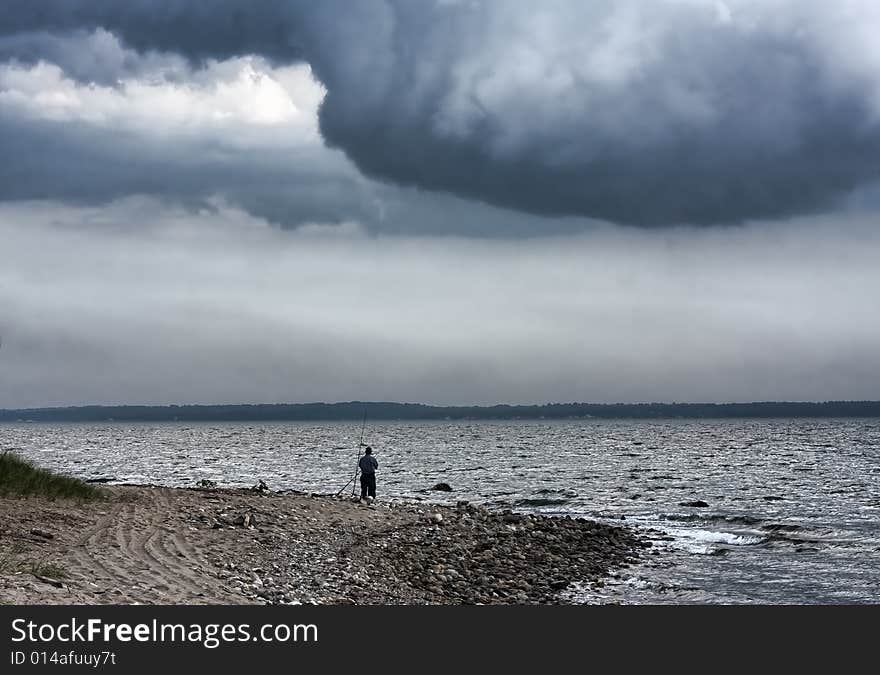 View of lone fisherman on the sound with distant storm clouds.