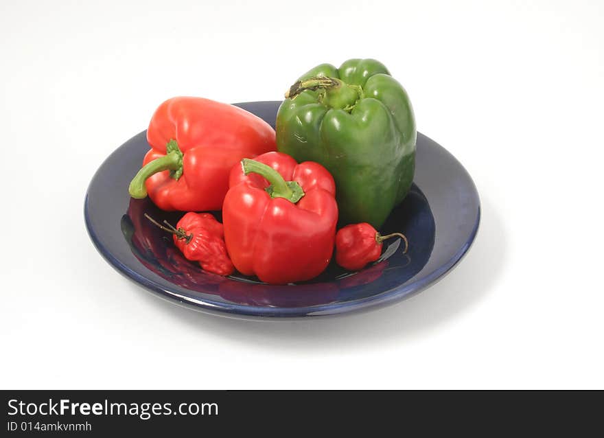 Isolated fresh assorted peppers on blue plate. Isolated fresh assorted peppers on blue plate