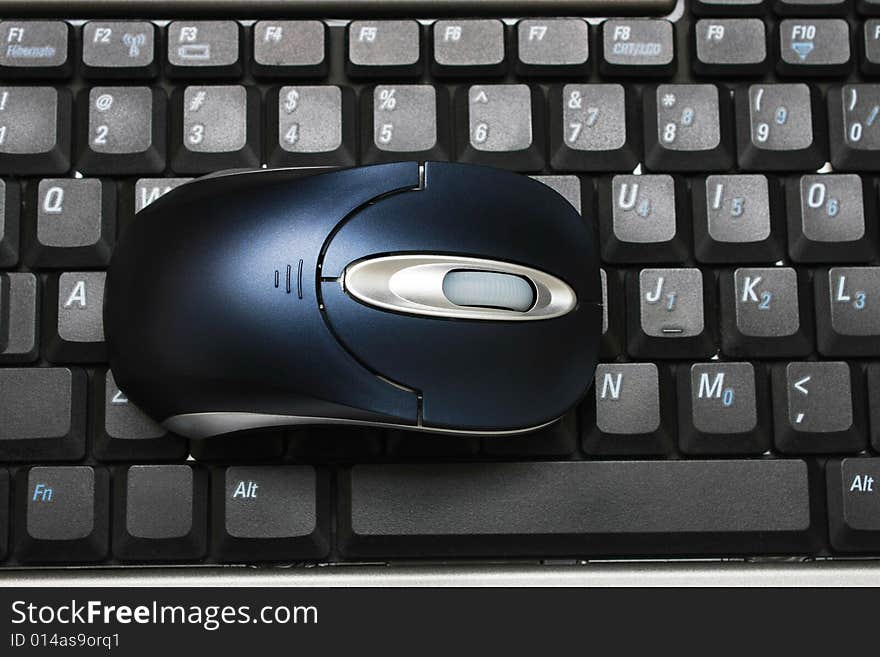 A wireless mouse put on keyboard of a laptop. A wireless mouse put on keyboard of a laptop.