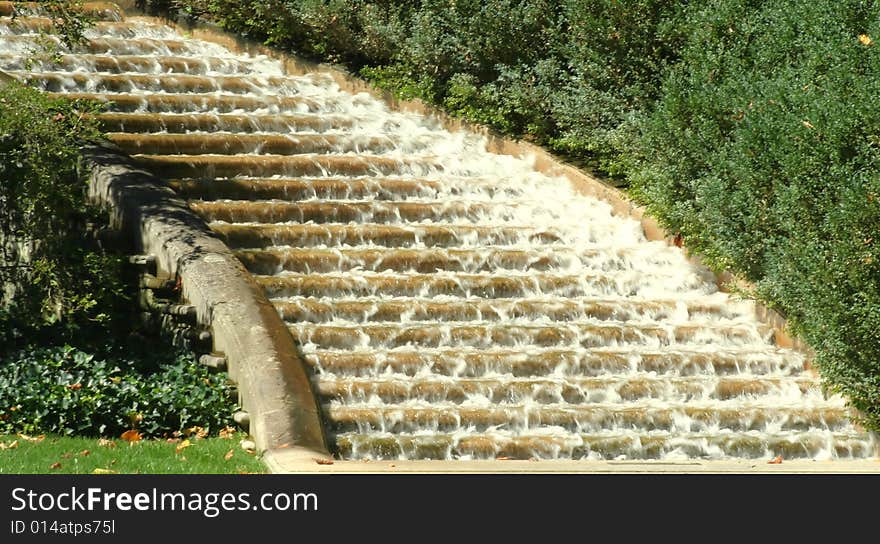 Water rushing down an outdoor flight of granite and concrete steps, surrounded by vegetation . Water rushing down an outdoor flight of granite and concrete steps, surrounded by vegetation