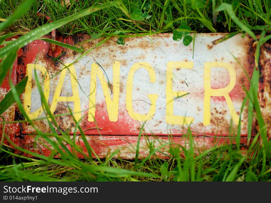 Danger sign slightly concealed in grass. Danger sign slightly concealed in grass