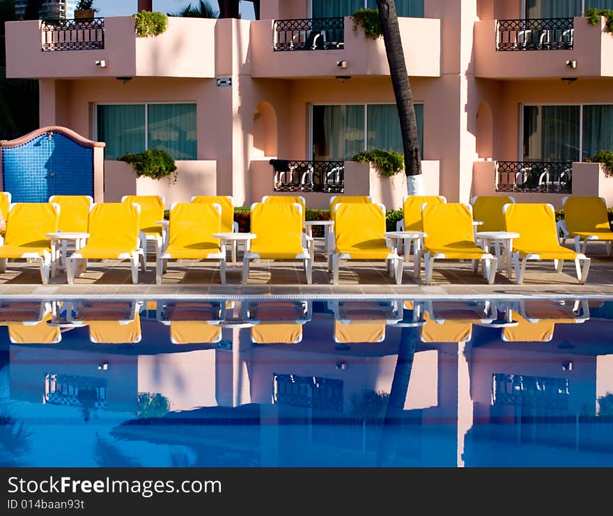 Yellow loungers reflecting in a swimming pool. Yellow loungers reflecting in a swimming pool.