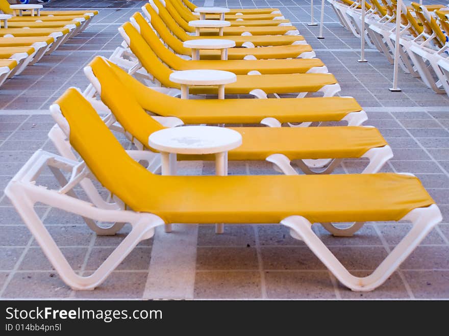 Yellow loungers next to a swimming pool.