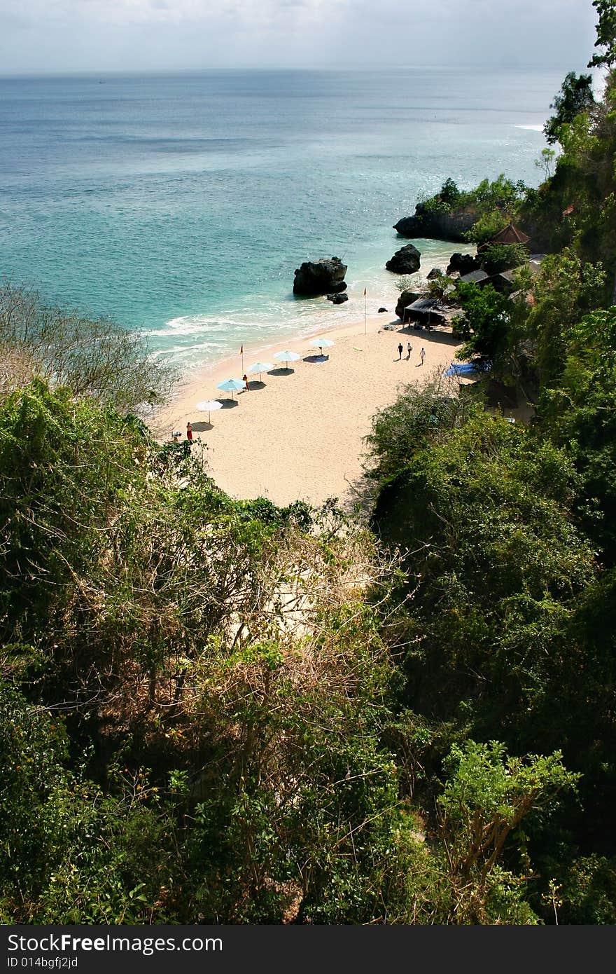 A beach with sunshades, green foliage and clear water. A beach with sunshades, green foliage and clear water.