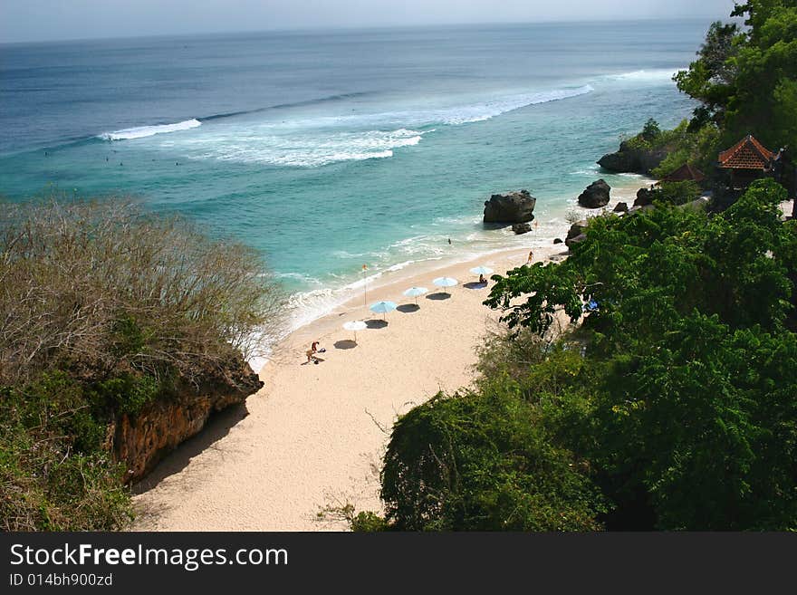 A beach with sunshades, green foliage and clear water. A beach with sunshades, green foliage and clear water.