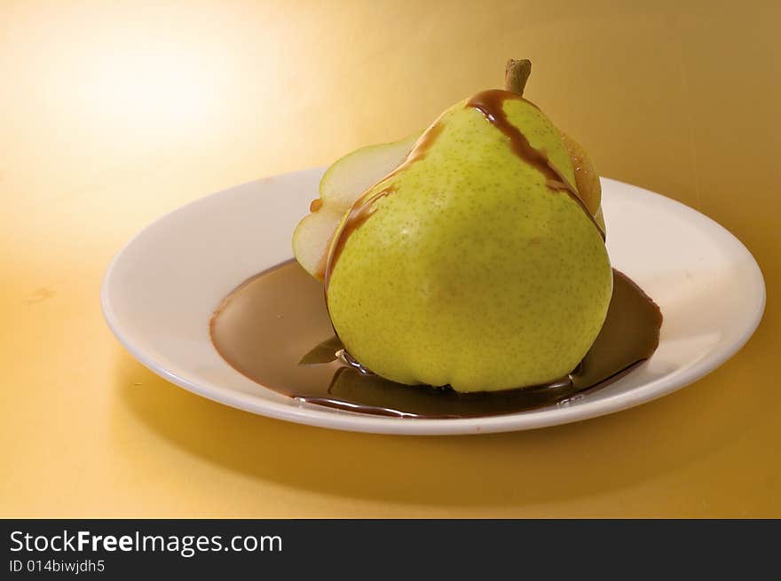 A sliced pear with chocolate sauce on a white plate