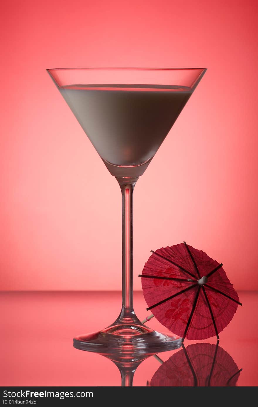 Milky cocktail with umbrella on red background