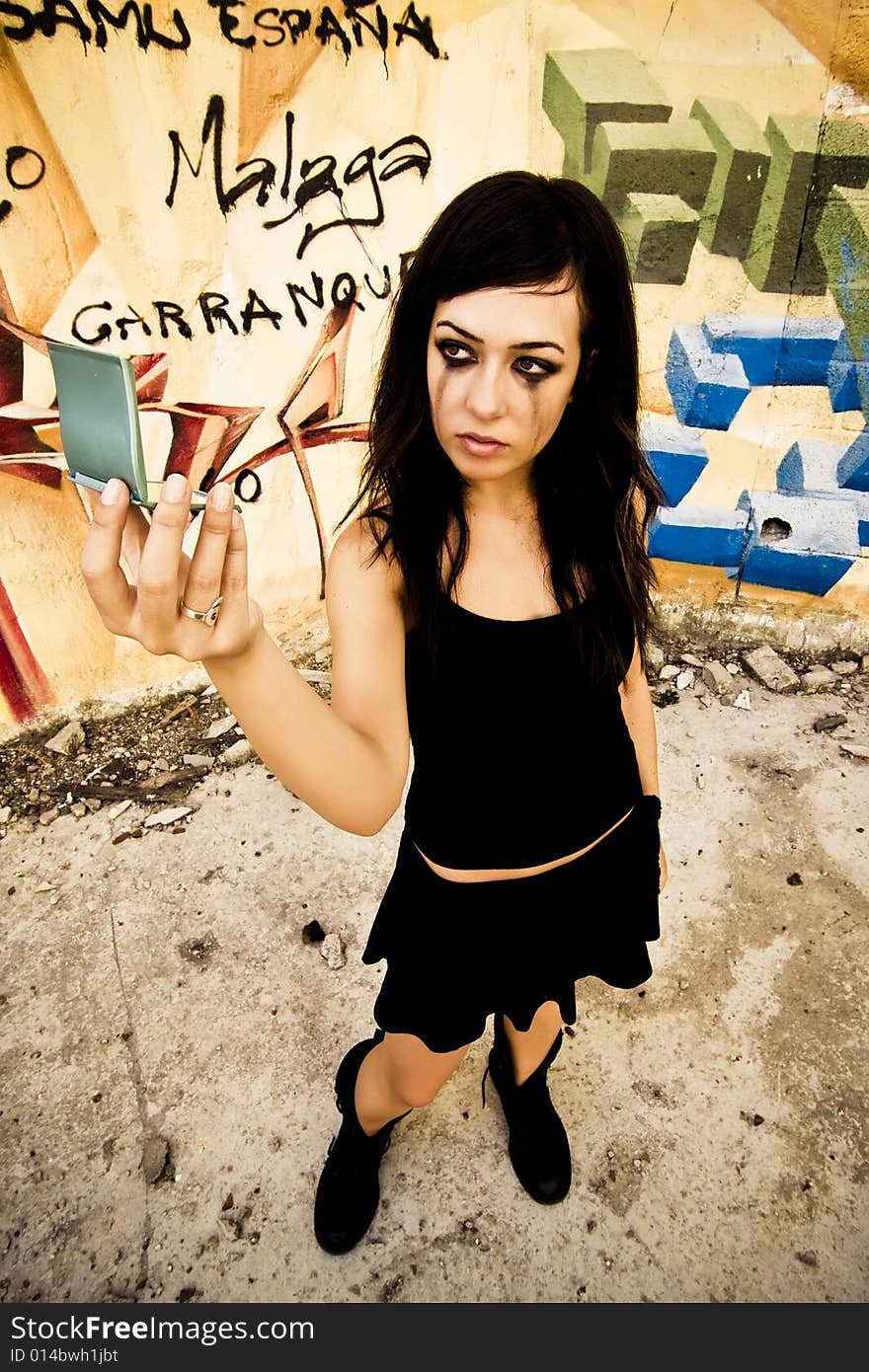 Goth girl looking mirror in urban background.