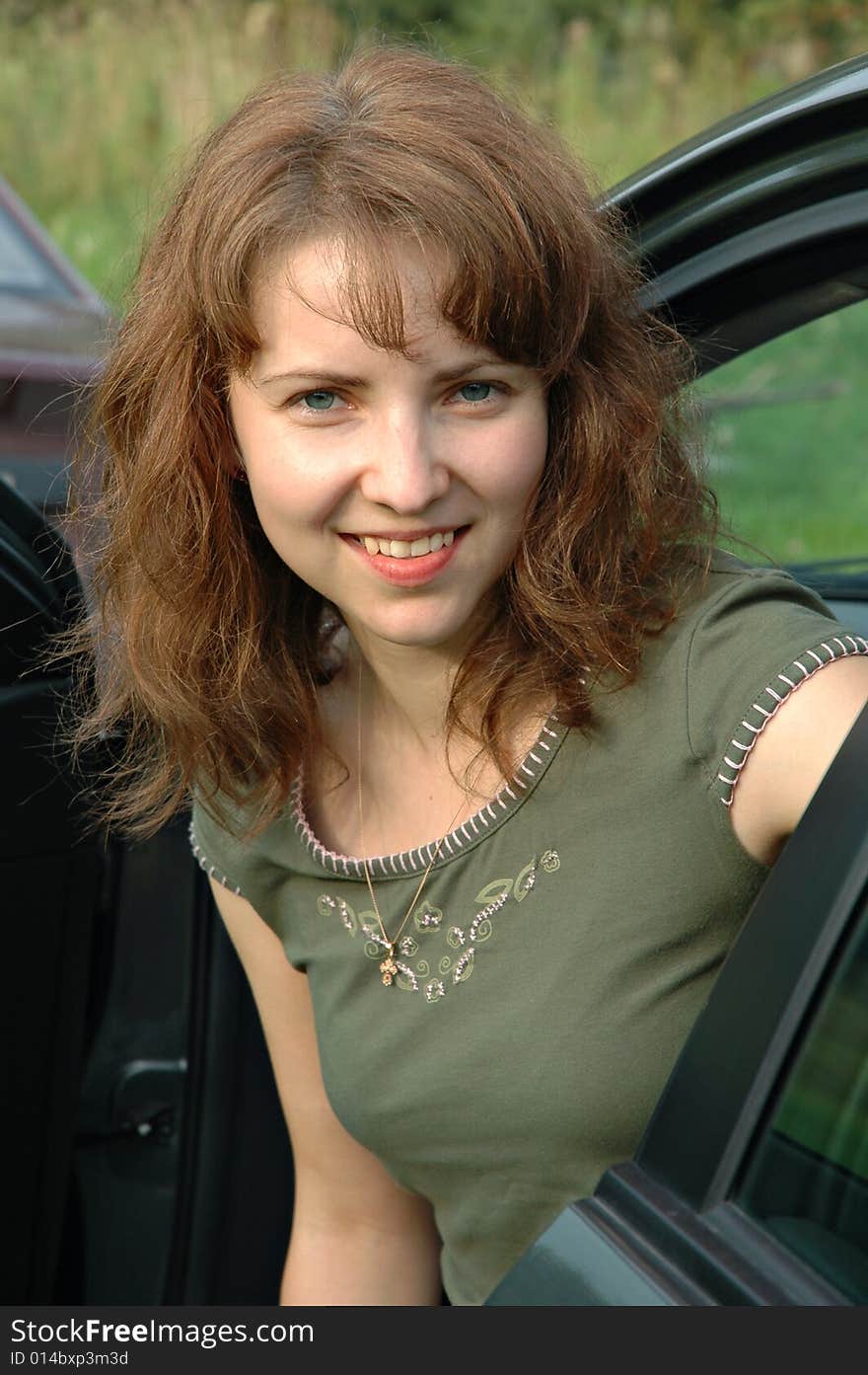 Portrait of smiling beautiful young woman exiting car door.