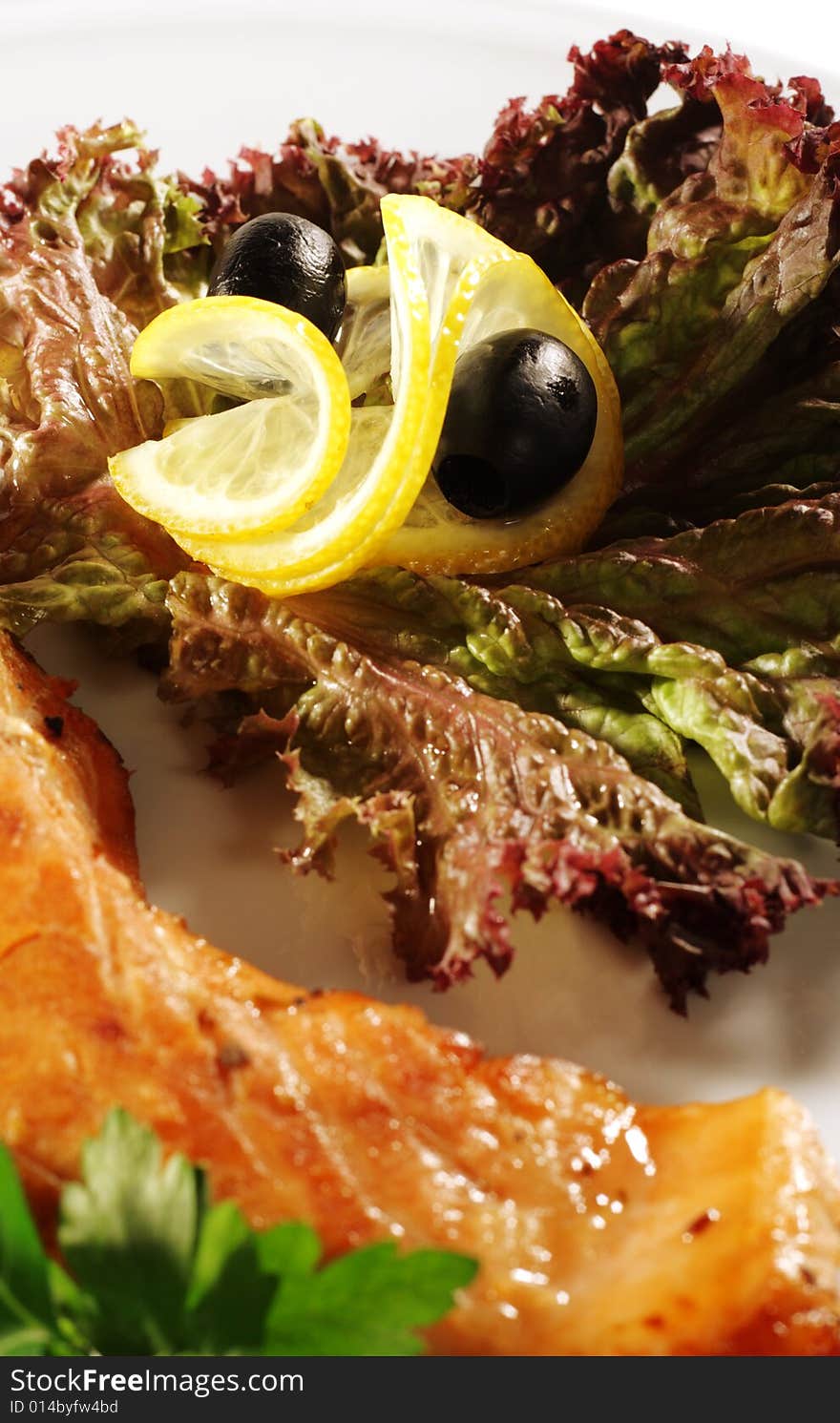 Steak from Filleted Fish (Salmon) with Lemon Slice Olive and Salad on a Plate. Isolated on White Background. Steak from Filleted Fish (Salmon) with Lemon Slice Olive and Salad on a Plate. Isolated on White Background